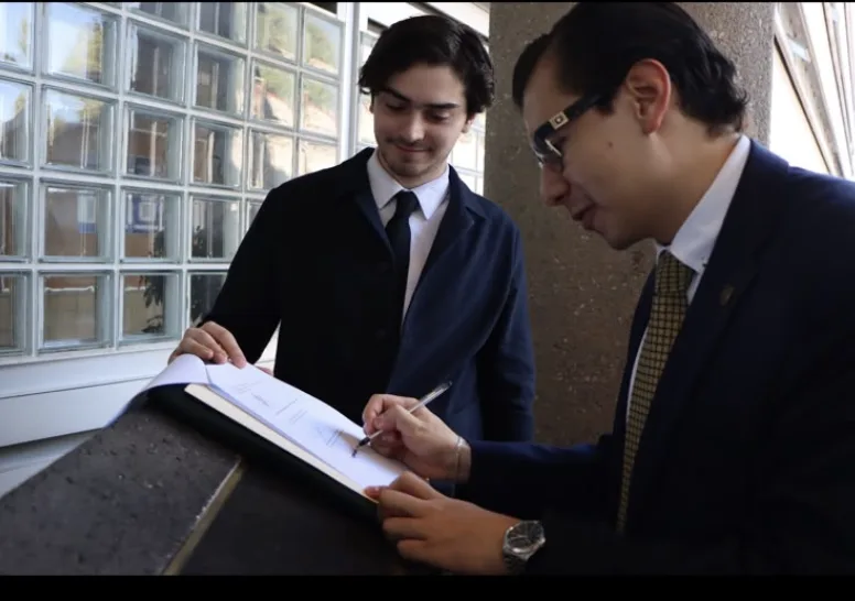Jorge Carbajal firmando un documento con un estudiante